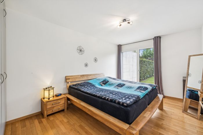 Helles Schlafzimmer mit Holzbett und Gartenblick